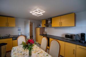 a kitchen with yellow cabinets and a table with flowers on it at Ferienwohnung Auerhahn in Lauterbach