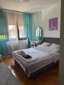 a bedroom with a large bed with blue curtains at Apartman Ristić in Pirot