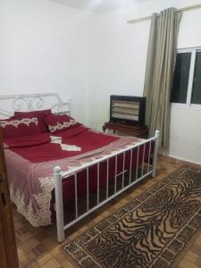 a bedroom with a bed with a red comforter at El Shibli Chalet in Jerash