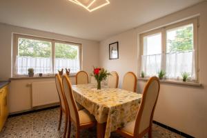 a dining room with a table and chairs and windows at Ferienwohnung Auerhahn in Lauterbach +17 photos