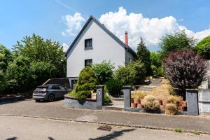 a white house with a car parked in a parking lot at Le Vogelgarten in Zellenberg