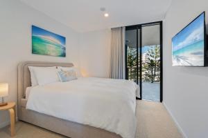 a white bedroom with a bed and a sliding glass door at Luxury Esprit Apartment at Rainbow Bay in Gold Coast +25 photos