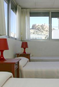 a hotel room with two beds and a window at Hotel Cervantes in Alicante