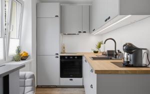 a white kitchen with white cabinets and a sink at Hygge House Elva in Elva