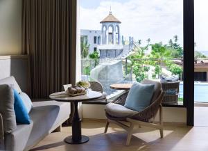 a living room with a couch and a table and a large window at Chatrium Phuket Rawai in Rawai Beach