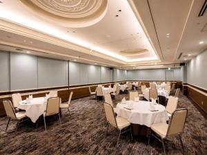 a dining room with white tables and chairs at Hotel JAL City Nagasaki in Nagasaki