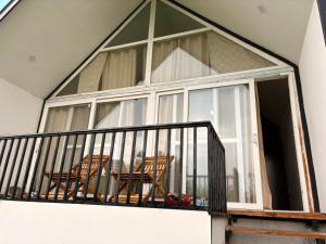a balcony with two chairs and a large window at Raiyar Resort doodhpathri in Rengazabal +9 photos