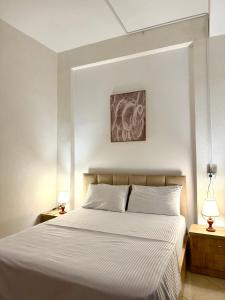 a bedroom with a large white bed with two lamps at ORA Appartment's in Shkodër