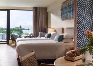 a hotel room with two beds and a balcony at Chatrium Phuket Rawai in Rawai Beach
