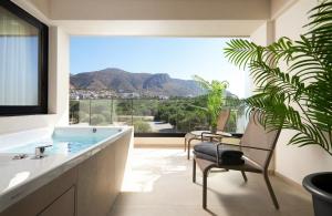 a bathroom with a tub and a plant and a window at Enorme Epavli Urban Living in Hersonissos