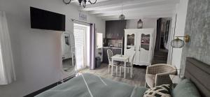a living room with a television and a kitchen at Gite "Le Cosy Fleuri" in Champenard
