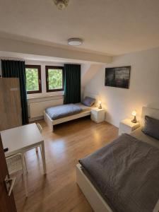 a bedroom with two beds and a desk and two windows at Stay Offenbach in Bürgel
