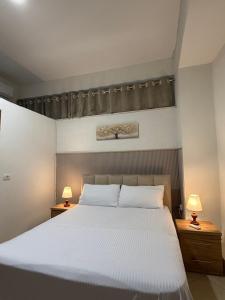 a bedroom with a large white bed with two lamps at ORA Appartment's in Shkodër