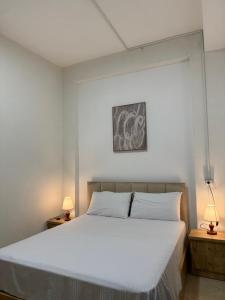 a bedroom with a white bed and two lamps at ORA Appartment's in Shkodër