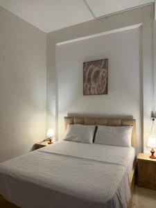 a bedroom with a large white bed with two lamps at ORA Appartment's in Shkodër