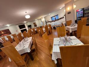 a dining room with white tables and wooden chairs at Mountain-Rest Pension in Miercurea-Ciuc