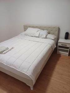 a bed with white sheets and pillows on it at Apartman Miljan in Trebinje