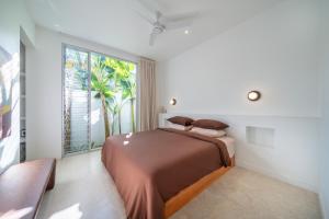a bedroom with a bed and a large window at Matahari House in Nusa Lembongan