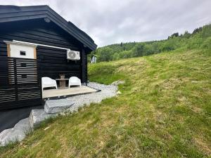 a black cabin with a table and two white chairs at Log cabin in Hodlekve with mountain view in Sogndal
