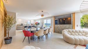 a dining room and living room with a table and chairs at Villa Panoramique - Lac du Bourget in Bourdeau