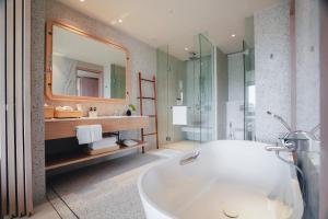 a bathroom with a tub and a sink and a mirror at Chatrium Phuket Rawai in Rawai Beach