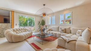 a living room with two couches and a table at Villa Panoramique - Lac du Bourget in Bourdeau