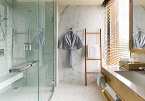 a bathroom with a glass shower and a sink at Chatrium Phuket Rawai in Rawai Beach