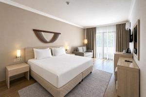 a bedroom with a large white bed and a chair at Rai Foresta Tekirova & SPA in Kemer