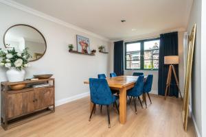 a dining room with a wooden table and blue chairs at A beautiful mews house in a city centre in Edinburgh