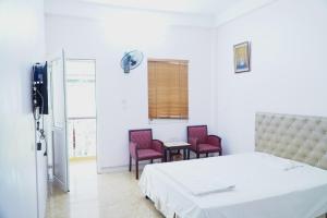 a bedroom with a bed and two chairs and a table at Ngày Mới Hotel in Nghĩa Lộ