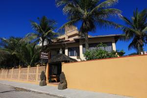 a building with palm trees behind a yellow fence at Hotel Kima in Bombinhas