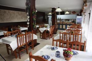 a restaurant with white tables and wooden chairs at Hotel Kima in Bombinhas