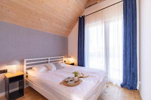 a bedroom with a white bed and a large window at Nadmorska Otulina - Nowoczesne dwupoziomowe domki nad morzem z dużym ogrodem in Ustka