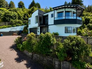 a house with a balcony on top of a brick driveway at Serendipity with a view in Taupo +7 photos