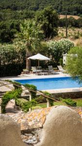 a swimming pool with chairs and an umbrella next to it at Agroturisme Son Cardaix in Artá