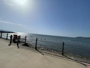 a person sitting on a bench looking at the water at 1 Marine House in Penzance