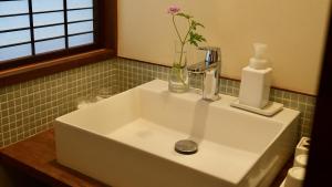 a bathroom sink with a vase with a flower in it at 一日一組 湘南の古民家貸別荘 Traditional Beach Villa, Quiet Seaside Stay, 10min Walk to Beach in Chigasaki +33 photos