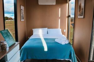 a bedroom with a bed with towels on it at Pasture and Paws by Tiny Away in Leeville