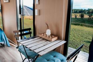 a table and chairs on a porch with a window at Pasture and Paws by Tiny Away in Leeville +17 photos
