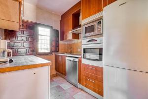a kitchen with white appliances and wooden cabinets at La Adrada Green Escape with pool in La Adrada