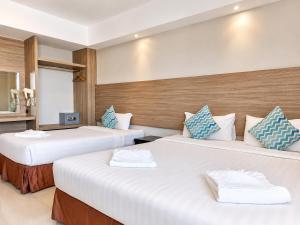 two beds in a hotel room with white and blue pillows at Avana Laem Chabang Boutique Hotel in Ban Laem Chabang