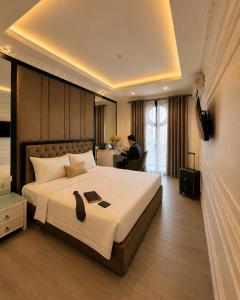 a hotel room with a bed and a man sitting at a desk at D'Élite Boutique Hotel Dĩ An in Dĩ An +51 photos