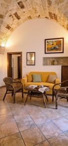 a living room with a yellow couch and chairs at La Corte di mezzo in Corigliano dʼOtranto