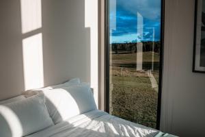 a bed sitting in a room with a window at Hills and Herds by Tiny Away in Shannon Brook