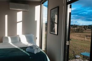 a bedroom with a bed and a large window at Hills and Herds by Tiny Away in Shannon Brook