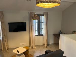 a living room with a tv and a couch and a window at Chez Elsa et Camille in Aigues-Mortes