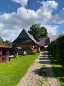 a log cabin with a gambrel roof on a yard at Apartament i Pokoje u Moniki in Witów