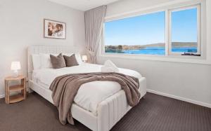 a white bedroom with a bed and a large window at Bayview Luxe Retreat in Tascott