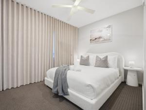 a white bedroom with a white bed and a window at Bayview Luxe Retreat in Tascott