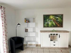 a living room with a white cabinet and a chair at Haus Wogemann III in Böhl